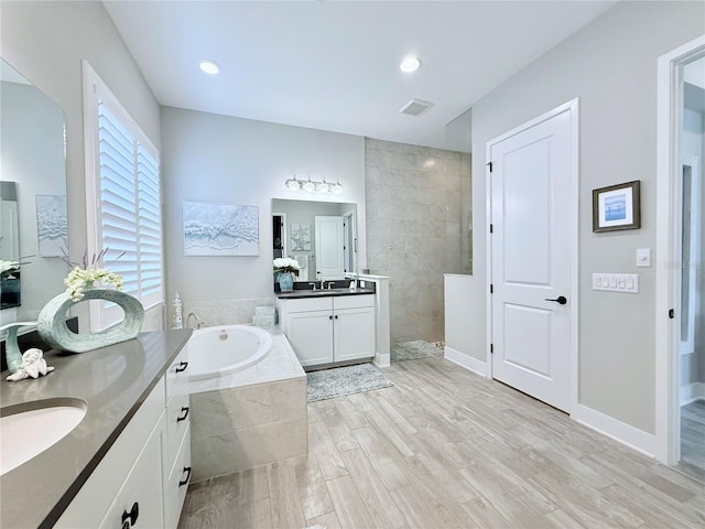 bathroom featuring hardwood / wood-style flooring, vanity, and plus walk in shower