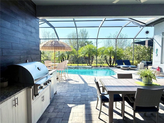 view of swimming pool featuring an outdoor kitchen, glass enclosure, grilling area, and a patio area