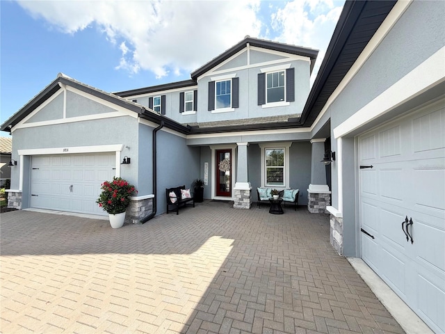 craftsman house with stone siding, decorative driveway, an attached garage, and stucco siding