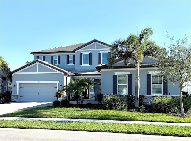 traditional-style home with stucco siding, an attached garage, a front yard, stone siding, and driveway