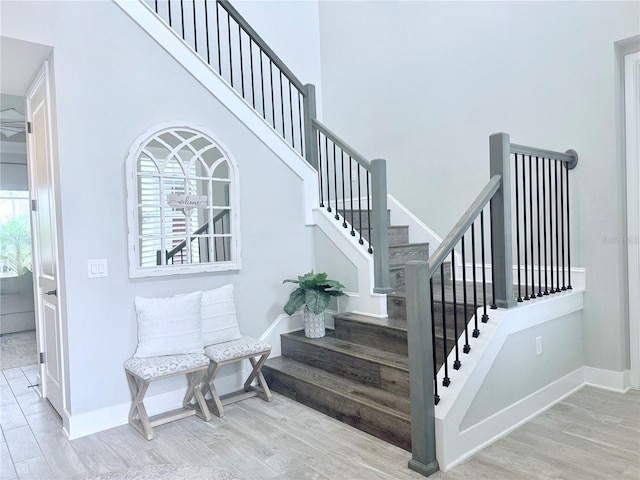 staircase with baseboards, a high ceiling, and wood finished floors