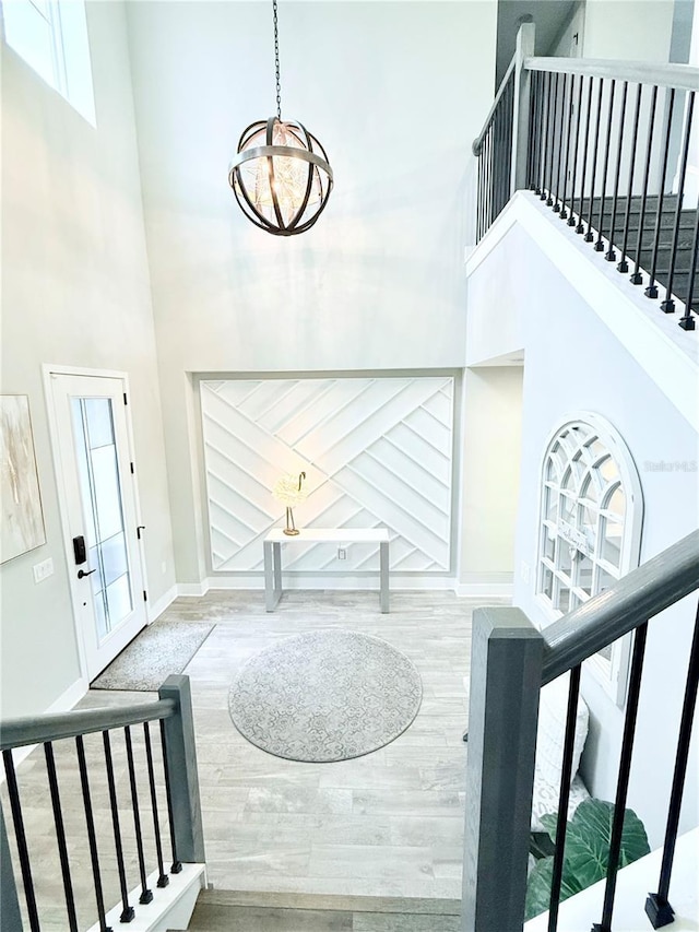 entryway featuring a notable chandelier, stairway, baseboards, and a towering ceiling