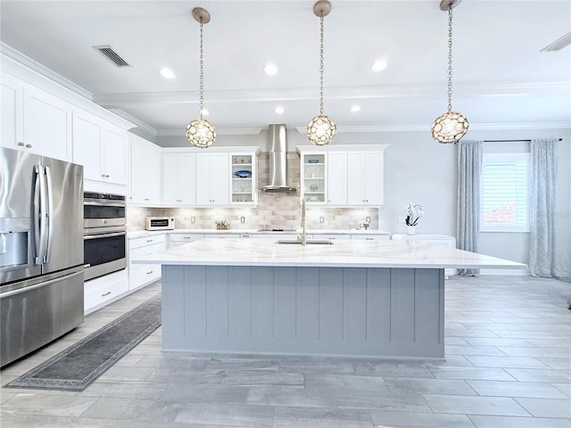 kitchen featuring backsplash, wall chimney range hood, beamed ceiling, an island with sink, and appliances with stainless steel finishes