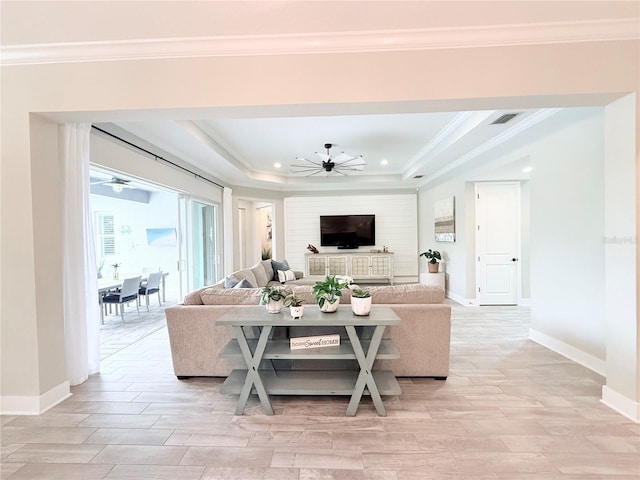 living room featuring a raised ceiling, a ceiling fan, and crown molding