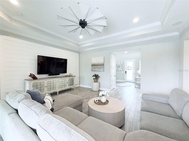 living area with a raised ceiling, ornamental molding, wood finished floors, recessed lighting, and baseboards