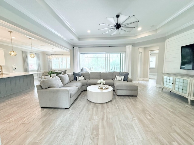 living room with a raised ceiling, recessed lighting, light wood-style floors, crown molding, and baseboards