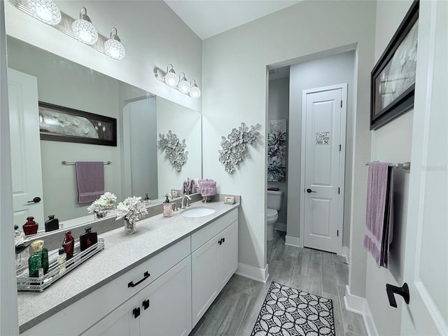 bathroom with vanity, toilet, and baseboards