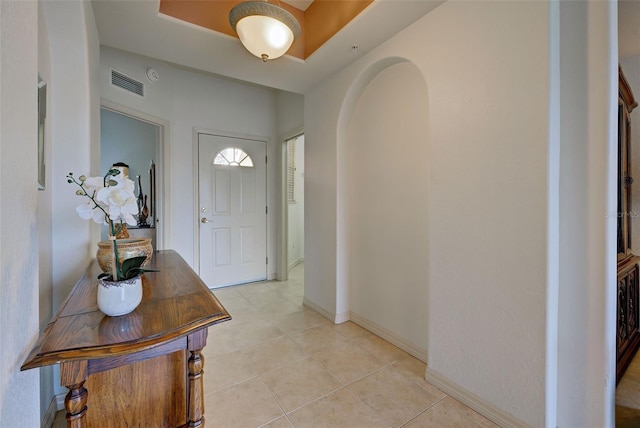 foyer with light tile patterned flooring and a tray ceiling