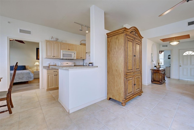 kitchen featuring light tile patterned floors, range, light brown cabinetry, and kitchen peninsula