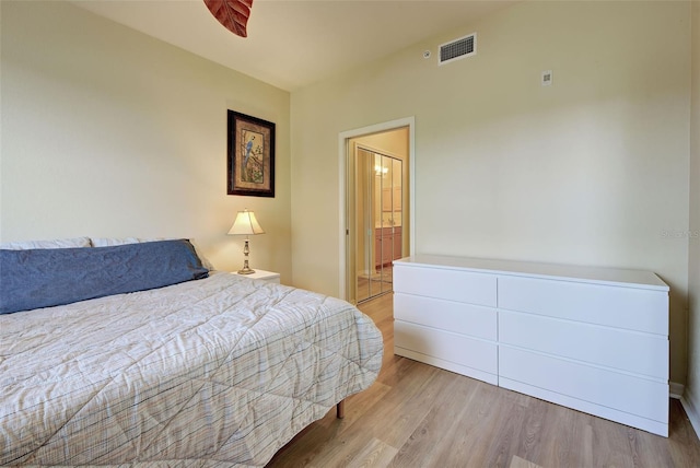 bedroom featuring connected bathroom and light hardwood / wood-style flooring