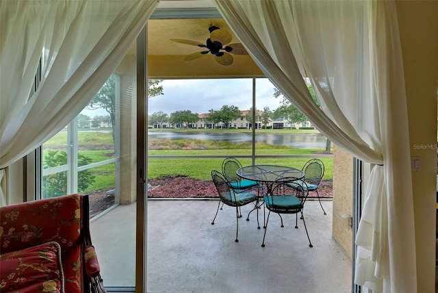 sunroom featuring a water view and ceiling fan