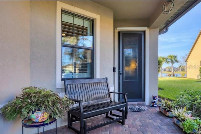 doorway to property featuring a patio area and a lawn