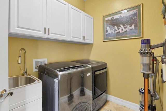 clothes washing area with sink, light tile patterned floors, cabinets, and washer and dryer