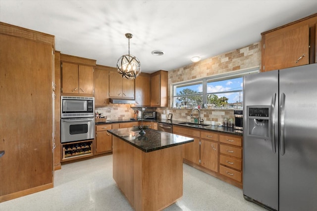 kitchen featuring sink, a center island, hanging light fixtures, appliances with stainless steel finishes, and decorative backsplash