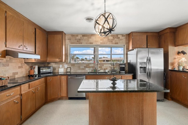 kitchen with decorative light fixtures, sink, decorative backsplash, a center island, and stainless steel appliances