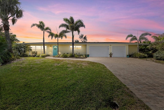 single story home with a garage and a lawn