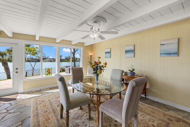 dining room with ceiling fan, beamed ceiling, and a water view