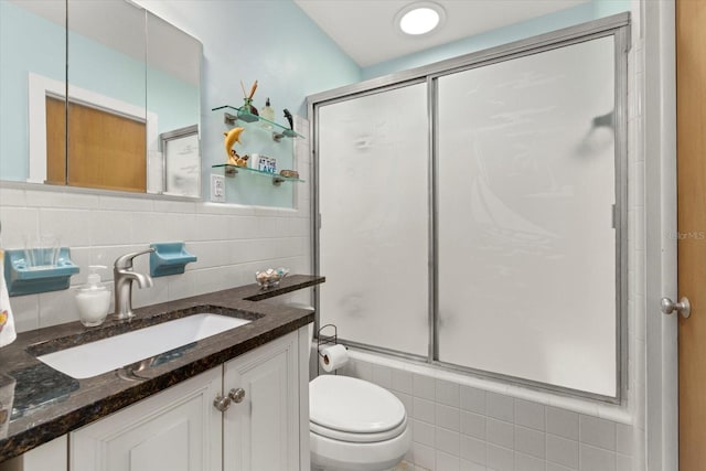 full bathroom featuring enclosed tub / shower combo, vanity, tile walls, and toilet