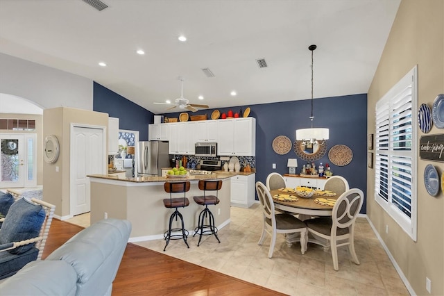 kitchen featuring a kitchen island, pendant lighting, white cabinetry, a breakfast bar area, and stainless steel appliances