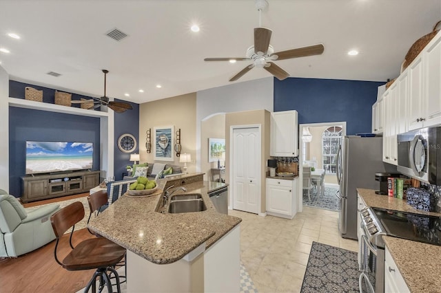 kitchen featuring a kitchen bar, sink, a center island with sink, appliances with stainless steel finishes, and white cabinets