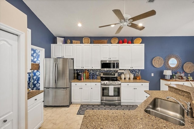 kitchen with white cabinetry, sink, backsplash, stainless steel appliances, and light stone countertops