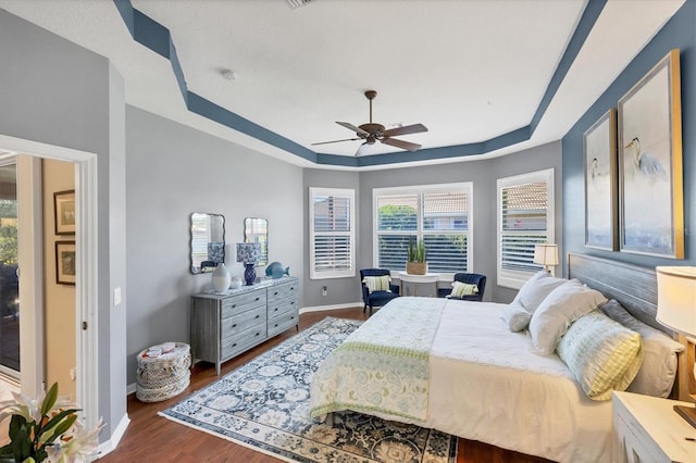 bedroom featuring dark hardwood / wood-style flooring, a raised ceiling, and ceiling fan