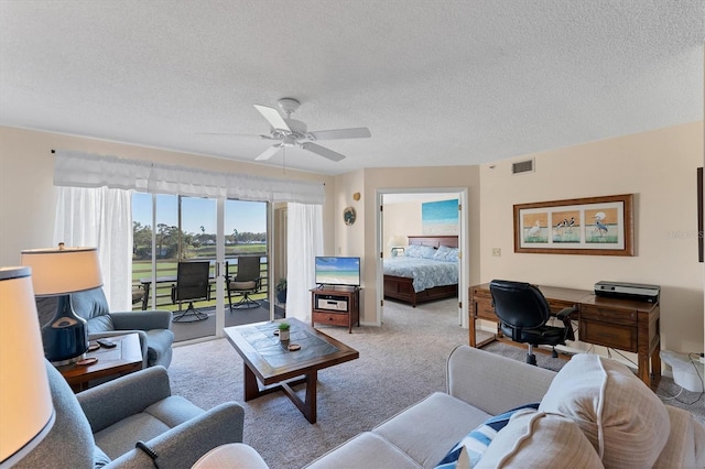 carpeted living room featuring ceiling fan and a textured ceiling