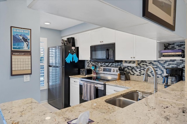 kitchen with appliances with stainless steel finishes, white cabinetry, sink, backsplash, and light stone counters