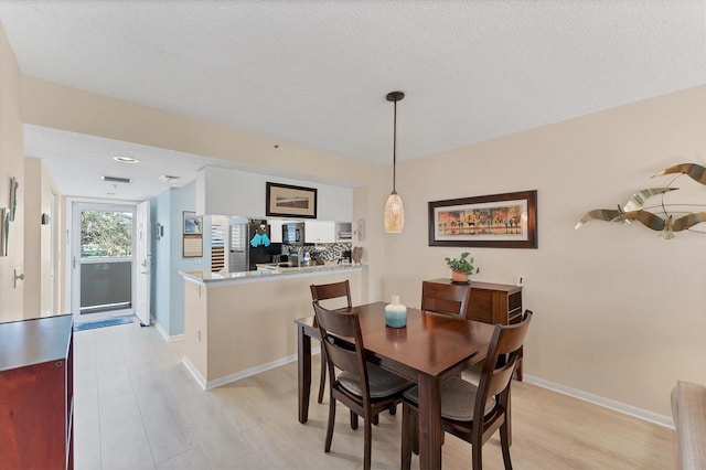 dining space featuring a textured ceiling and light hardwood / wood-style flooring