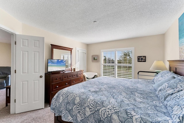 bedroom with light colored carpet and a textured ceiling