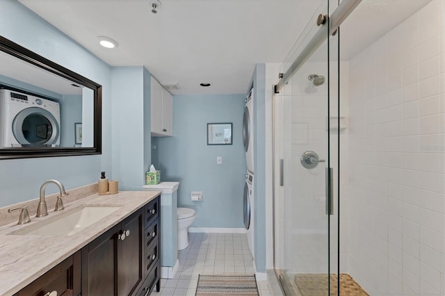 bathroom featuring walk in shower, toilet, vanity, stacked washing maching and dryer, and tile patterned flooring