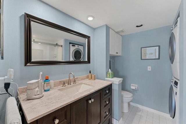 bathroom featuring tile patterned flooring, vanity, stacked washer / drying machine, an enclosed shower, and toilet