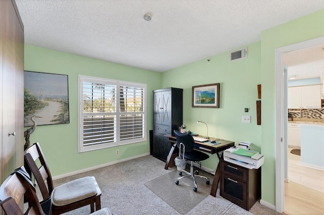 office space with light carpet and a textured ceiling