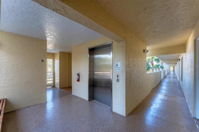 hallway featuring a textured ceiling and elevator