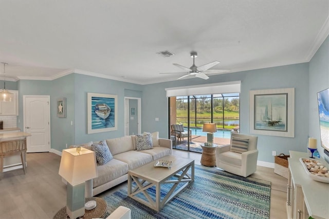 living room with ornamental molding, ceiling fan, and light wood-type flooring