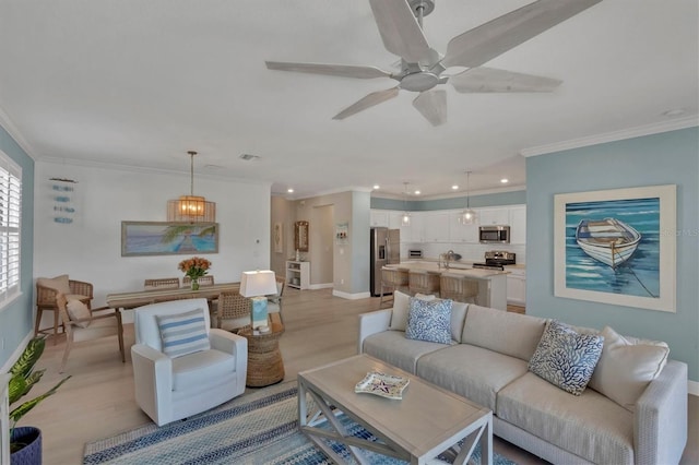 living room with crown molding, ceiling fan, sink, and light wood-type flooring