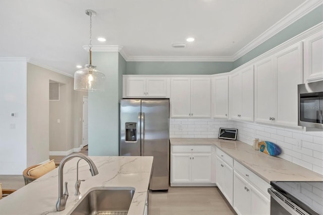 kitchen featuring hanging light fixtures, white cabinetry, appliances with stainless steel finishes, and light stone counters