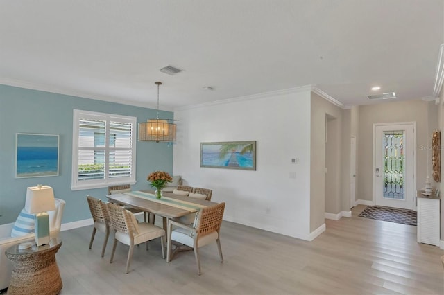 dining area with crown molding, a chandelier, and light wood-type flooring