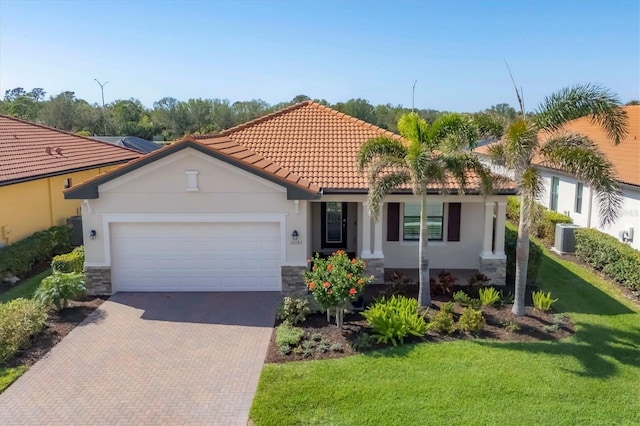 mediterranean / spanish house with a garage, a front yard, and central AC unit