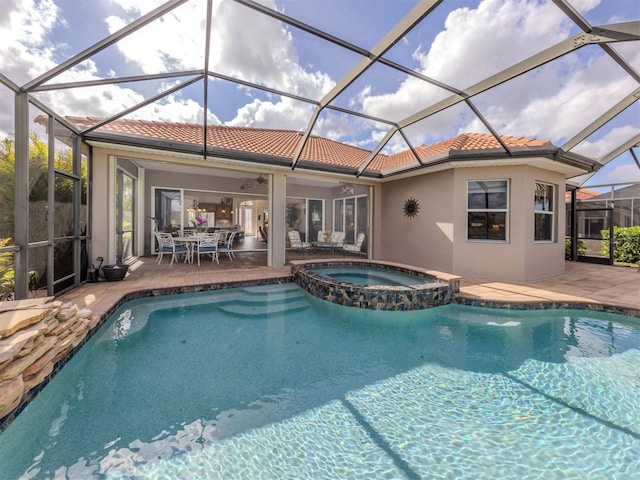 view of pool with a patio, glass enclosure, and an in ground hot tub