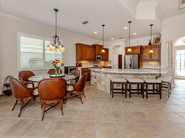 tiled dining room with an inviting chandelier, ornamental molding, and sink