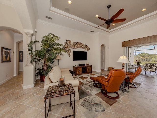 living room with light tile patterned floors, ornamental molding, a raised ceiling, a towering ceiling, and ceiling fan