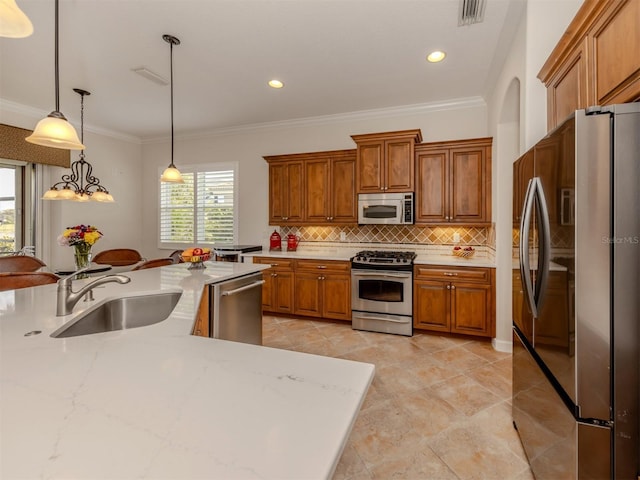 kitchen with appliances with stainless steel finishes, decorative light fixtures, sink, decorative backsplash, and light stone counters