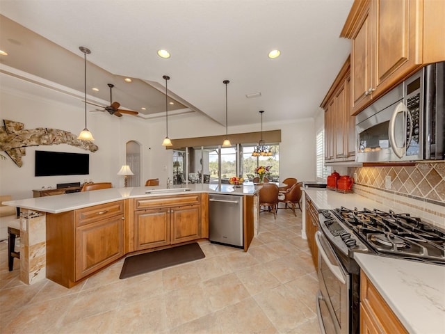 kitchen featuring pendant lighting, crown molding, appliances with stainless steel finishes, a kitchen bar, and decorative backsplash