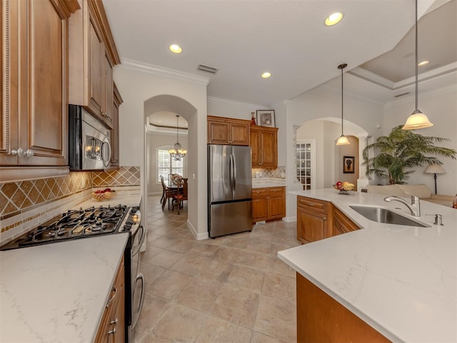 kitchen featuring appliances with stainless steel finishes, tasteful backsplash, sink, hanging light fixtures, and ornamental molding