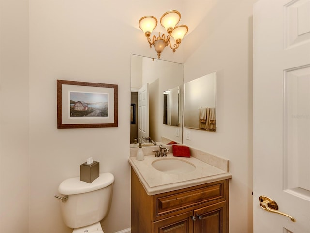 bathroom featuring vanity, toilet, and a notable chandelier