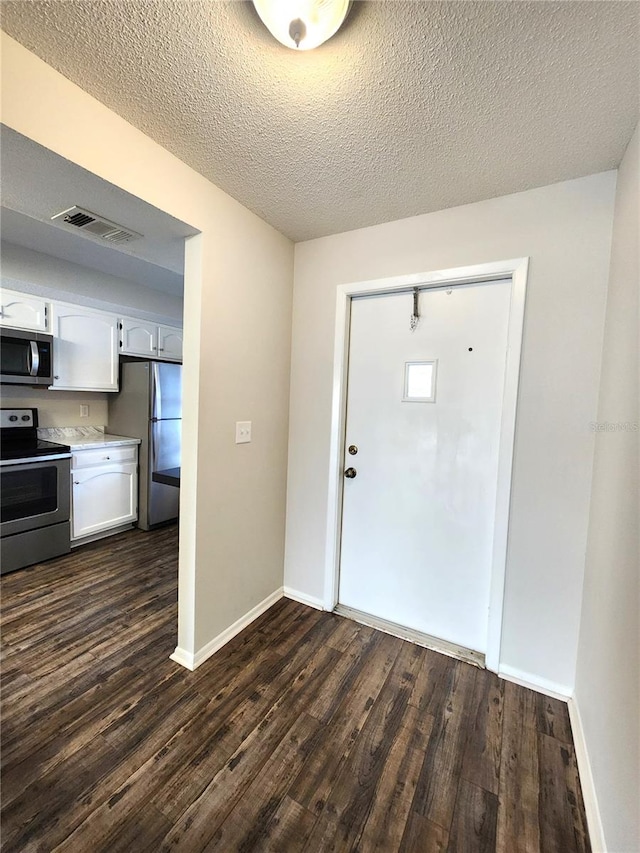 entryway with visible vents, baseboards, a textured ceiling, and dark wood-style floors