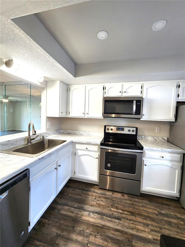 kitchen with a ceiling fan, a sink, dark wood-style floors, appliances with stainless steel finishes, and white cabinets