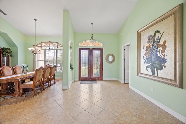 tiled foyer entrance featuring a notable chandelier, french doors, and lofted ceiling