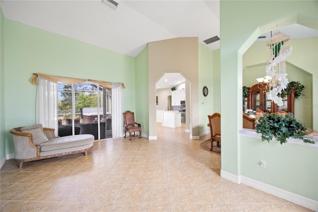 living area with high vaulted ceiling, light tile patterned floors, and an inviting chandelier